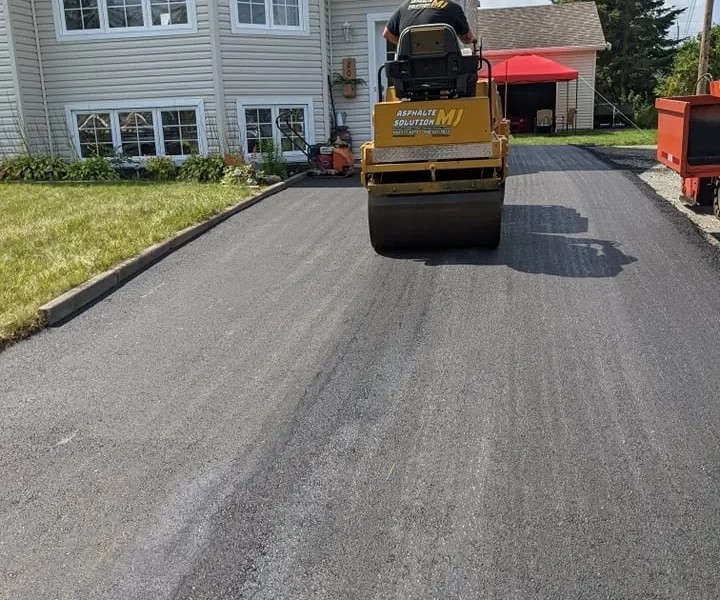 Rouleau compacteur pavant une entrée résidentielle