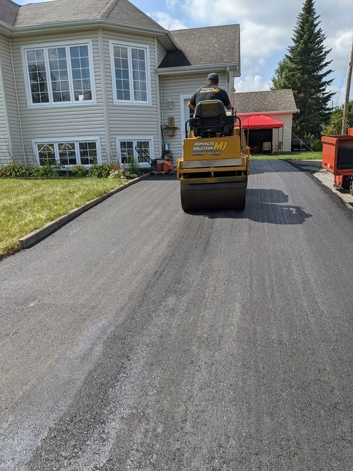 Rouleau compacteur pavant une entrée résidentielle
